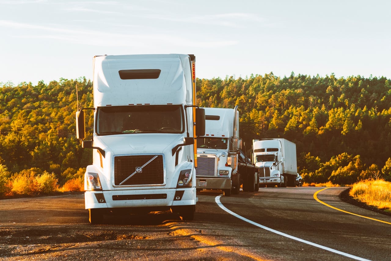 Contact Three semi trucks driving on a highway through a forested landscape in Arizona.